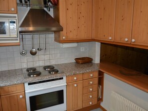 Eine Küche mit Holzausstattung, einer Granitarbeitsplatte, einem Herd und einer Mikrowelle.