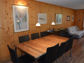 Ein Zimmer mit Holzwänden, einem Esstisch, Stühlen und Kunstwerken an den Wänden.