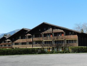 A traditional chalet-style building with multiple balconies, a gravel driveway, and a mountainous backdrop. - Oberland Nr. 3 Appartement/Fewo, Dusche oder Bad, WC 8-Bettwohnung by Interhome (Gstaad)