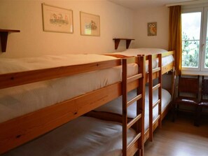 Ein Zimmer mit Etagenbetten, einem Schreibtisch und zwei gerahmten Bildern an der Wand.