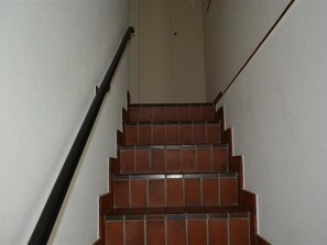 Eine Treppe mit roten Fliesen und einem schwarzen Geländer.