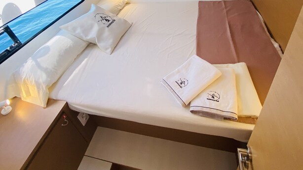A compact, well-lit room with a bed, pillows, and neatly folded towels. - Sun-Kissed Sailing: A Luxurious Beach Experience in Valencia (Denia)