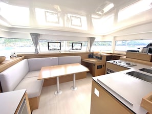 A compact kitchen with a dining area, a stove, and a sink. - Sun-Kissed Sailing: A Luxurious Beach Experience in Valencia (Denia)