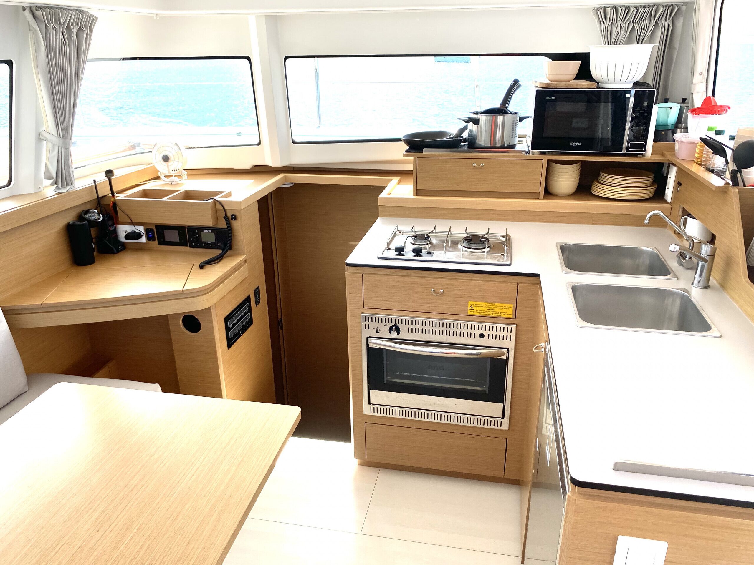 A compact galley kitchen with a microwave, stove, oven, and two sinks.