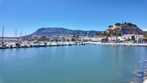 A marina with boats docked, a mountain in the background, and buildings along the waterfront. - Sun-Kissed Sailing: A Luxurious Beach Experience in Valencia (Denia)