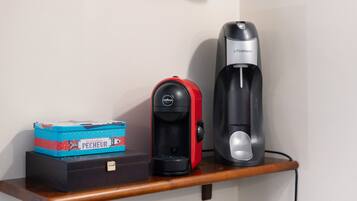 Une machine à café, une boîte étiquetée « Pêcheur » et un appareil noir posé sur une étagère en bois.