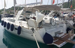 A sailboat named 'Oceanis 45' docked at a marina with a covered deck and multiple lifebuoys.