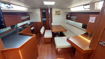 A compact galley with a stove, sink, and storage cabinets. There is a small seating area with a bench and a table.