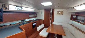 A compact galley with a sink, stove, and storage cabinets. There is a small seating area with a bench and a table.