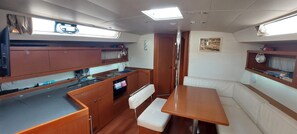 A compact galley with a sink, stove, and storage cabinets. There is a small seating area with a bench and a table.