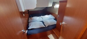 Une petite cabine comprenant un lit, une petite fenêtre et une porte.
