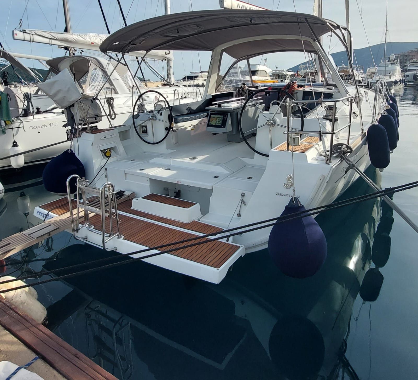 Un yate amarrado en un puerto deportivo, con cubierta protegida, timón y panel de control.