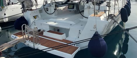 Un yate amarrado en un puerto deportivo, con cubierta protegida, timón y panel de control.