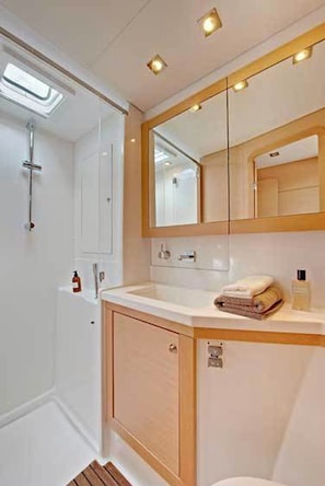 A bathroom with a shower, a mirror, a sink, and a toilet. - Sun-Kissed Sailing Adventure in Islas Sarónicas (Alimos)