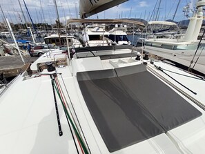 Een jachthaven met meerdere boten afgemeerd, een overdekt gebied met zitplaatsen en uitzicht op het water en land in de verte.