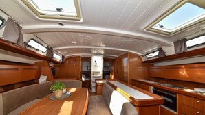 A boat interior with a dining area, seating, and a galley with a stove. - Sun-Kissed Sailing Adventure in Zadar, Croatia (Bibinje)