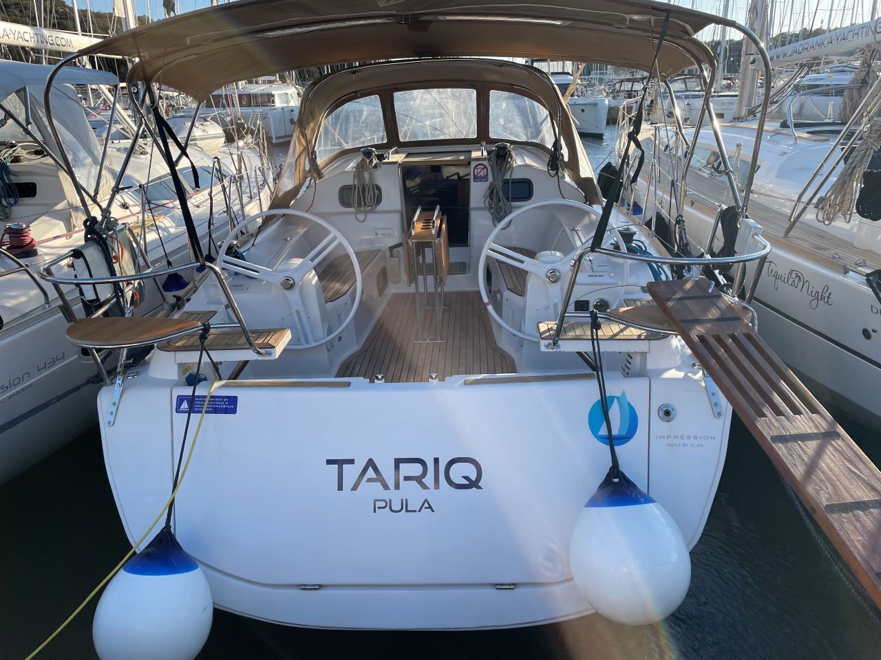 Ein Boot namens 'TARIQ PULA' liegt in einer Marina zusammen mit anderen Booten vor Anker.