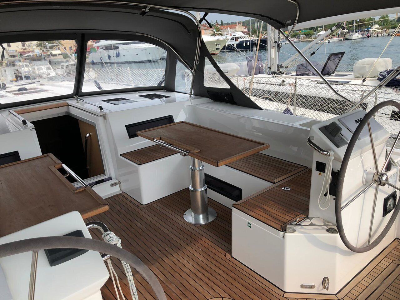 Das Deck einer Yacht mit Tisch, Sitzgelegenheiten und Steuer.