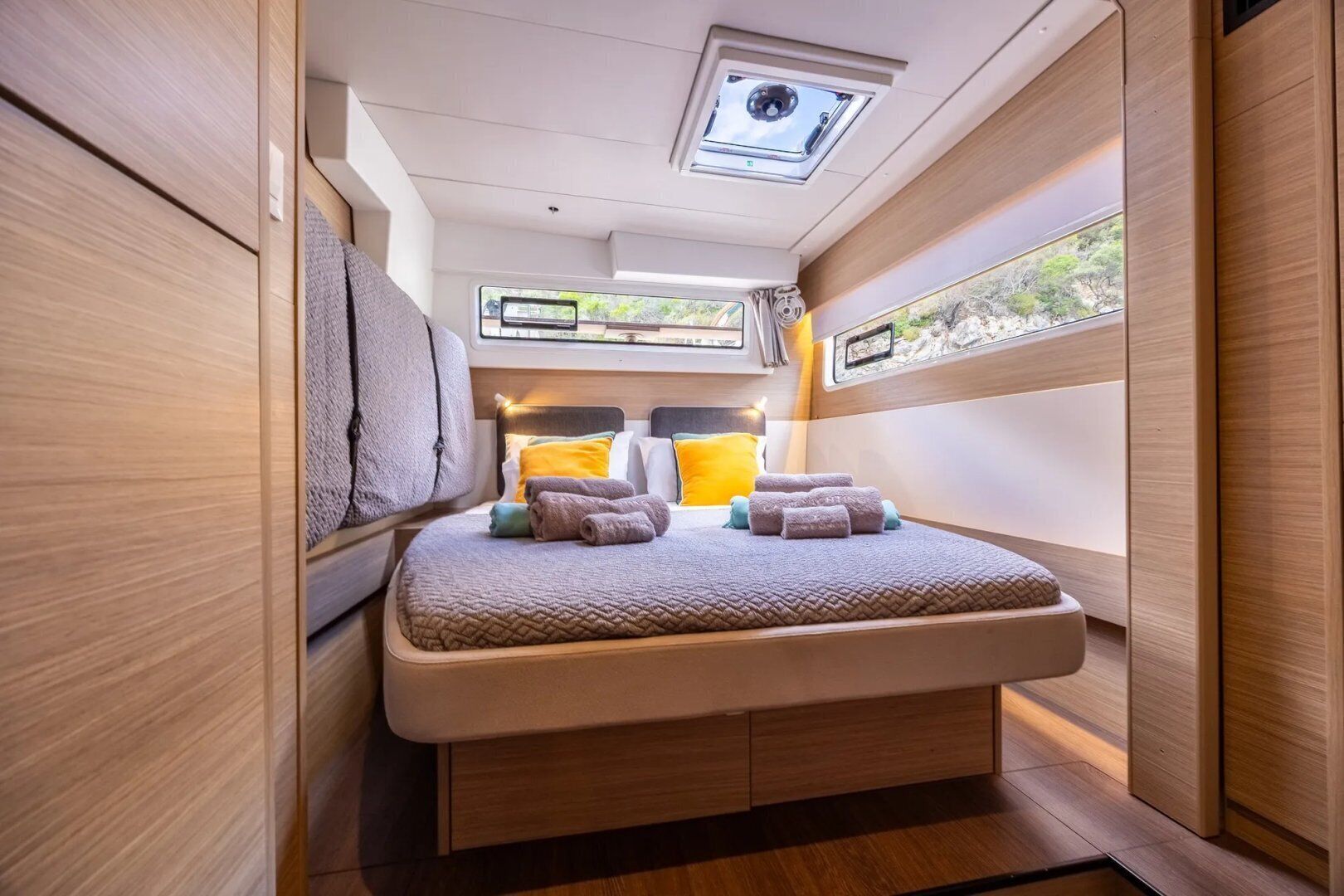 A compact, well-lit interior with a bunk bed, a skylight, and a window providing a view of the outdoors.
