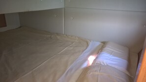 A bed with a white mattress and beige bedding, a wooden headboard, and a plain wall. - Sibenik Sun and Beach Sailing Extravaganza: A Croatian Coastal Adventure (Jezera)