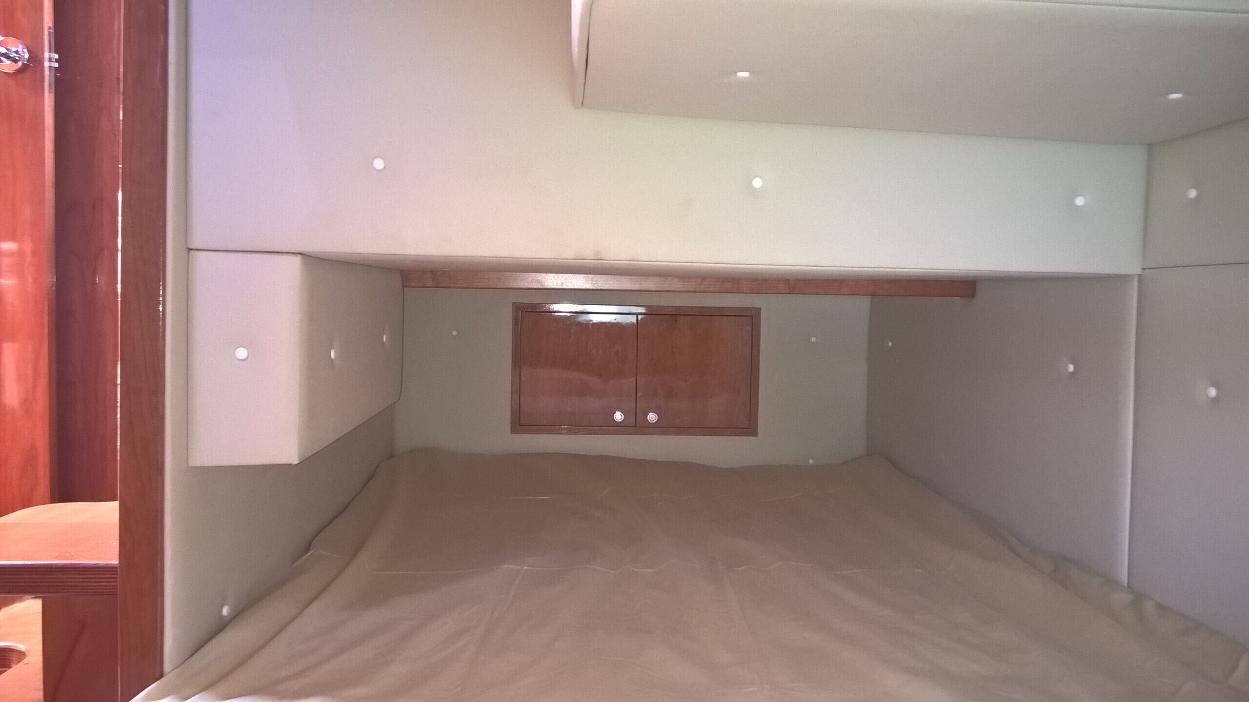 A bunk bed with a wooden headboard and a small window.