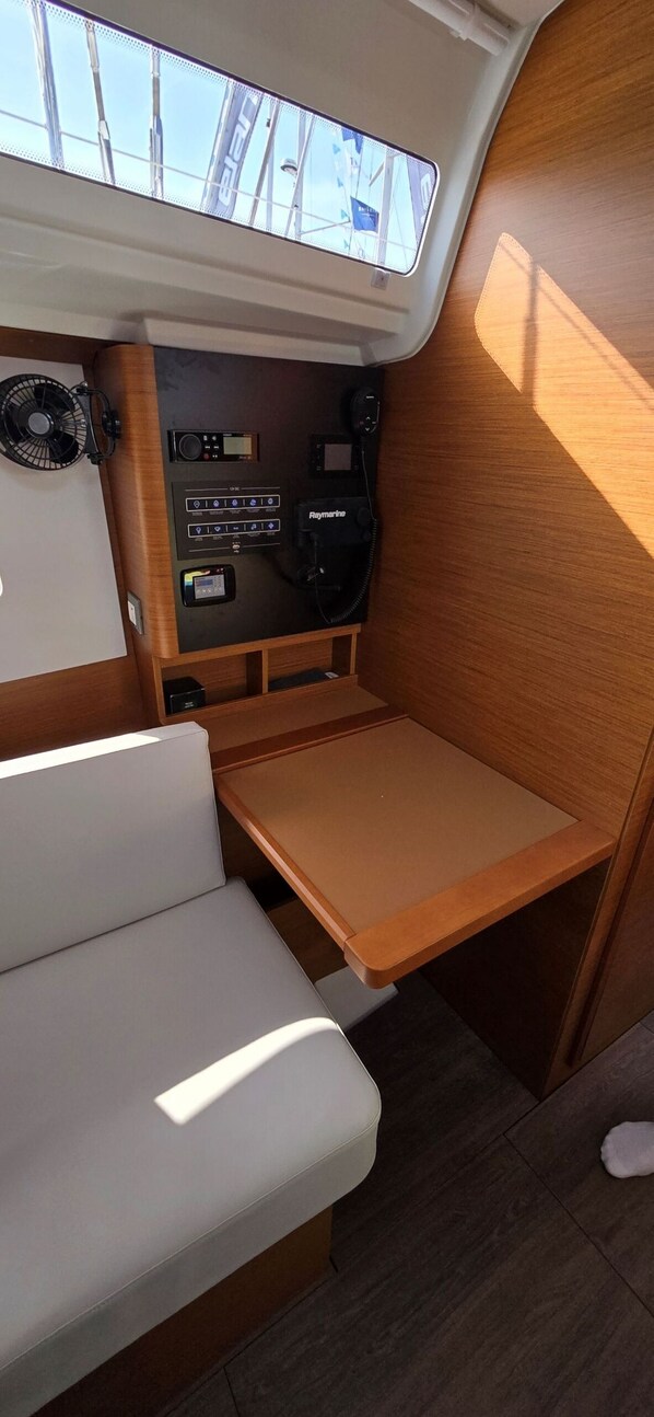 A compact boat interior with a cushioned seating area, a control panel with various buttons and displays, and a skylight above. - Sun-Kissed Sailing Adventure in Istria, Croatia (Pula)