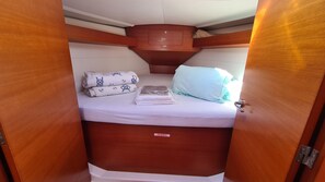 Une cabine compacte comprenant un lit, des oreillers et un espace de rangement pour les gilets de sauvetage.