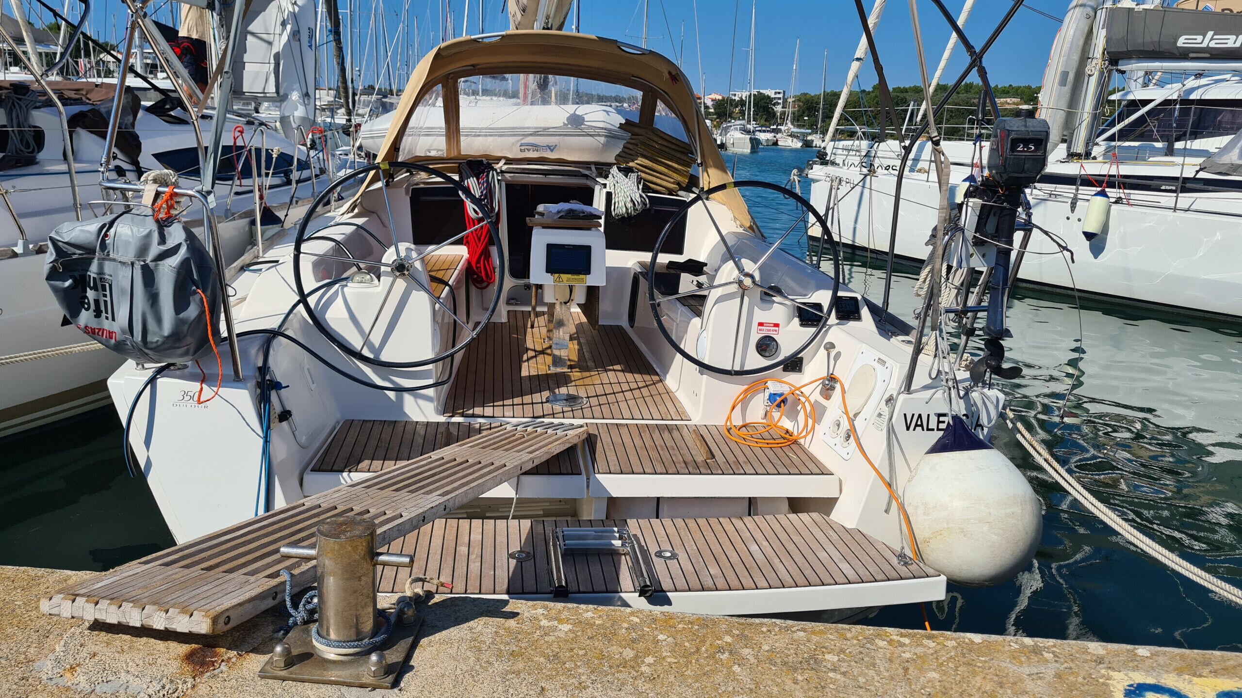 Das Deck eines Bootes mit Steuerrad, Armaturenbrett und einer kleinen Holzplattform.