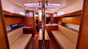A narrow interior with wooden paneling, a central aisle, and seating areas on either side. - Sun-Kissed Sailing Adventure in Sibenik, Croatia (Zaton)