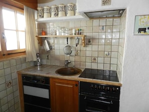 A kitchen with a sink, stove, oven, and various kitchen utensils. - Media Appartement/Fewo, Dusche oder Bad, WC 6-Bettwohnung by Interhome (Gstaad)