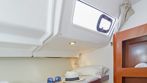 Een stapelbed met dakraam, een houten plank en een klein houten kastje.