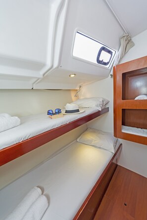 Un lit superposé avec une lucarne, une étagère en bois et une petite armoire en bois.