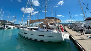 A marina with multiple sailboats docked, a clear blue sky, and a calm water surface. - Sun-Kissed Sailing Adventure in Gran Barrera de Coral from Playa Airlie, Queensland (Airlie Beach)