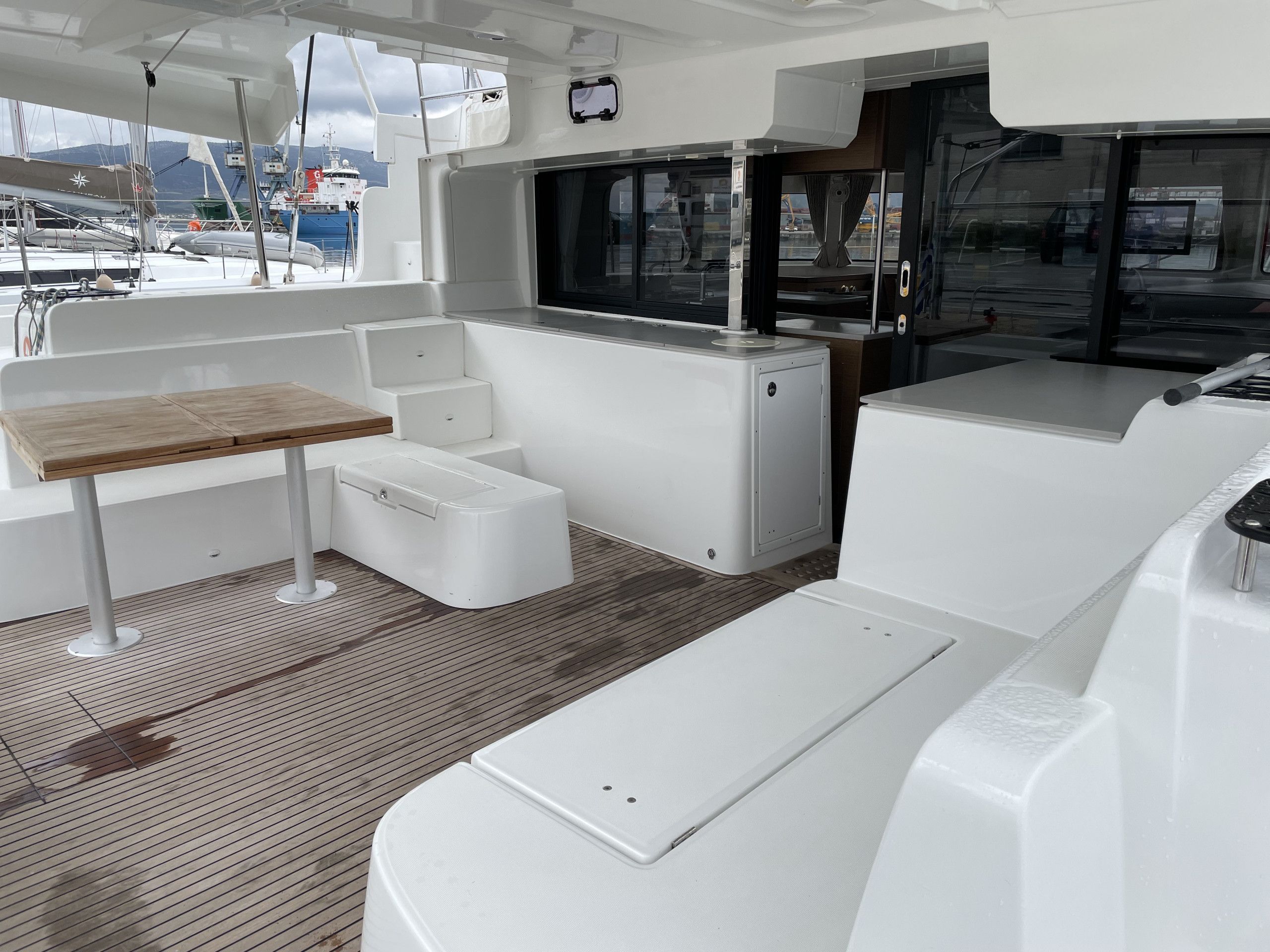 A boat's interior with a table, seating, and a view of the marina.