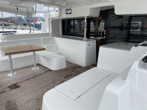 A boat's interior with a table, seating, and a view of the marina.