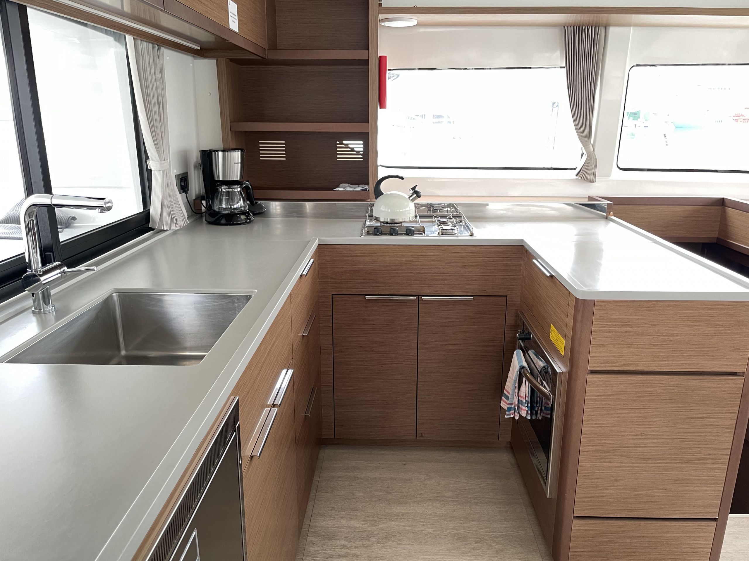 Cocina compacta con electrodomésticos de acero inoxidable, armarios de madera y una ventana que proporciona luz natural.