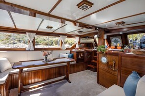 Ein gemütliches Blockhaus-Interieur mit einer hölzernen Bank, einem Tisch und einer Barbereich mit Flaschen und Gläsern.