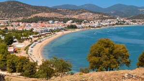 Una località costiera con spiaggia, mare cristallino e montagne sullo sfondo.