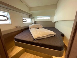 A compact, well-lit interior with a single bed, a window, and a small seating area. - Sibenik Sun-soaked Sailing: A Luxurious Croatian Voyage (Pirovac)