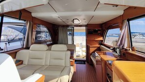 A boat interior with a seating area, a small kitchen, and a view of the water outside. - Sun-Kissed Sailing Adventure in Zadar, Croatia (Bibinje)