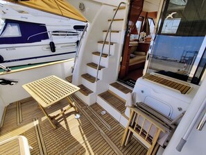 Ein kompakter, gut beleuchteter Innenraum mit einem Holzboden, einem kleinen Tisch und einer Treppe, die zu einem erhöhten Deckbereich führt.