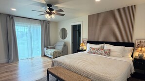 A bedroom with a bed, a bench, a ceiling fan, a bedside table, and a view through a window. - Cozy 2-bedroom house in adorable Mohnton with AC (Mohnton)