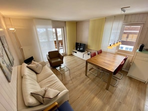 Een moderne woonkamer met een bank, een eettafel en een televisie.