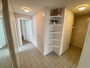 A hallway with a white wardrobe, a shelf with flowers, and a door with a notice. - Suzanne Nr. 22 Appartement/Fewo, Dusche oder Bad, WC 4-Bettwohnung by Interhome (Gstaad)
