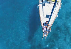 Vue aérienne d’un voilier sur une mer d’un bleu profond.