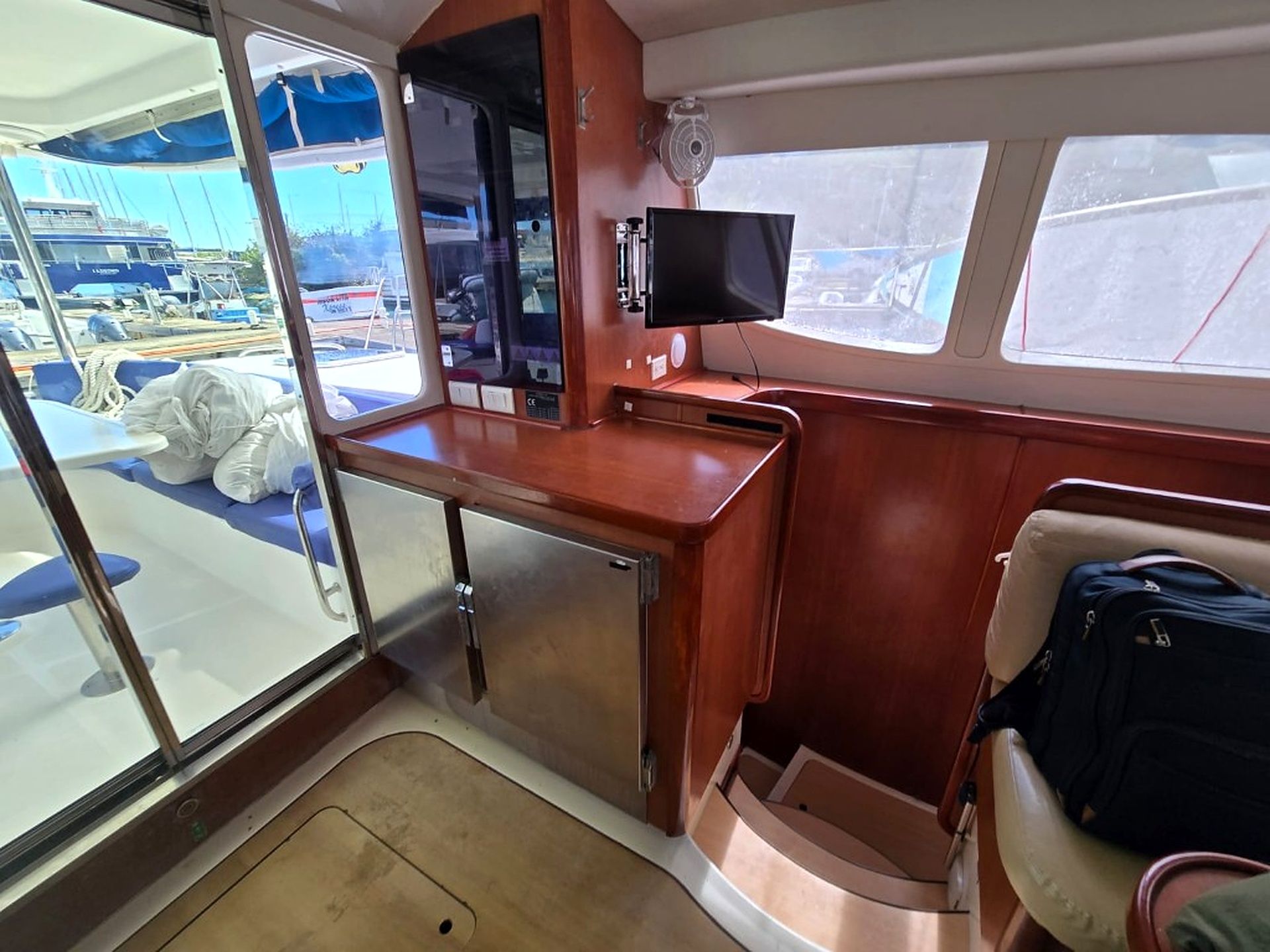 Une petite cabine comprenant un coin cuisine, un téléviseur et une fenêtre donnant sur un port de plaisance.