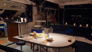 A dining area with a table set for two, a sofa, and candles. - Caribbean Bliss: Sun-soaked Sailing Adventure from San Vicente y las Granadinas (Ribishi)