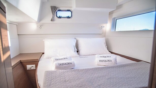 A bedroom with a bed, two pillows, a nightstand, a window, and a small skylight. - Sun-kissed Sailing Adventure in the Ionian Islands (Preveza)