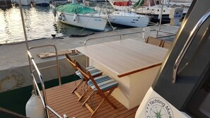 A boat deck with a wooden table, two striped chairs, and a railing. - Sun-Kissed Sailing Adventure in Zadar, Croatia (Kukljica)