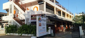 A multi-story building with a staircase, balconies, and various signs including one for a liquor store.